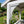 White painted wooden porch support bracket and post in a landscaped garden setting with flowers and greenery.
